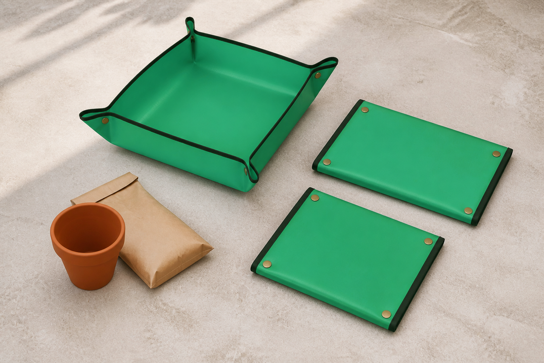 Exactly three green repotting mats: one snapped into a shallow workspace and two folded flat beside it